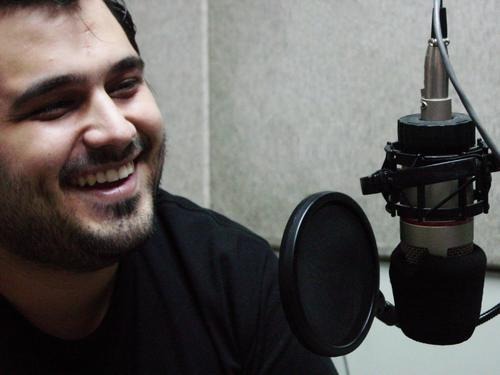 Hombre sonriente frente al micrófono dentro de un estudio de radio